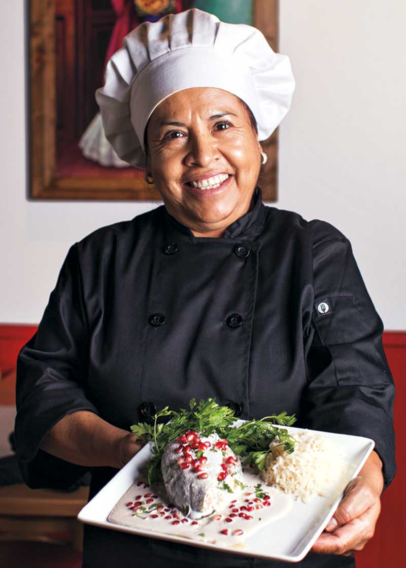 owner Guadalupe Escobar holding chiles en nogada (seasonal)
