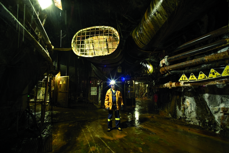 Seppala stands in shaft No. 10, surrounded by pipes pumping hot air and water out of the mine and pumping in cool air. Photo by Mark Lipczynski