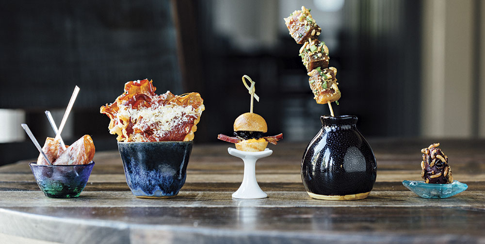 Left to right: Salami- wrapped olives; crispy serrano ham and aged Gouda; lamb bacon slider; candied pork belly; foie gras-stuffed date; Photo by Blake Bonillas