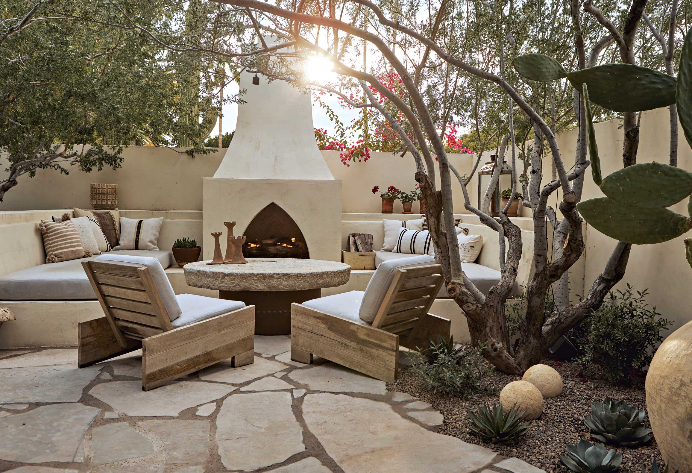 A Moroccan-influenced fireplace, in keeping with the home’s unique history, flanked by banco seating provides a focal point for outdoor entertaining. A round millstone coffee table was sourced by Grant and his partner, David Michael Miller, on a buying trip to Los Angeles. “Grant has a wonderful eye for beautiful objects and collectibles,” adds landscape designer Charlie Ray. A Moroccan-influenced fireplace, in keeping with the home’s unique history, flanked by banco seating provides a focal point for outdoor entertaining. A round millstone coffee table was sourced by Grant and his partner, David Michael Miller, on a buying trip to Los Angeles. “Grant has a wonderful eye for beautiful objects and collectibles,” adds landscape designer Charlie Ray.