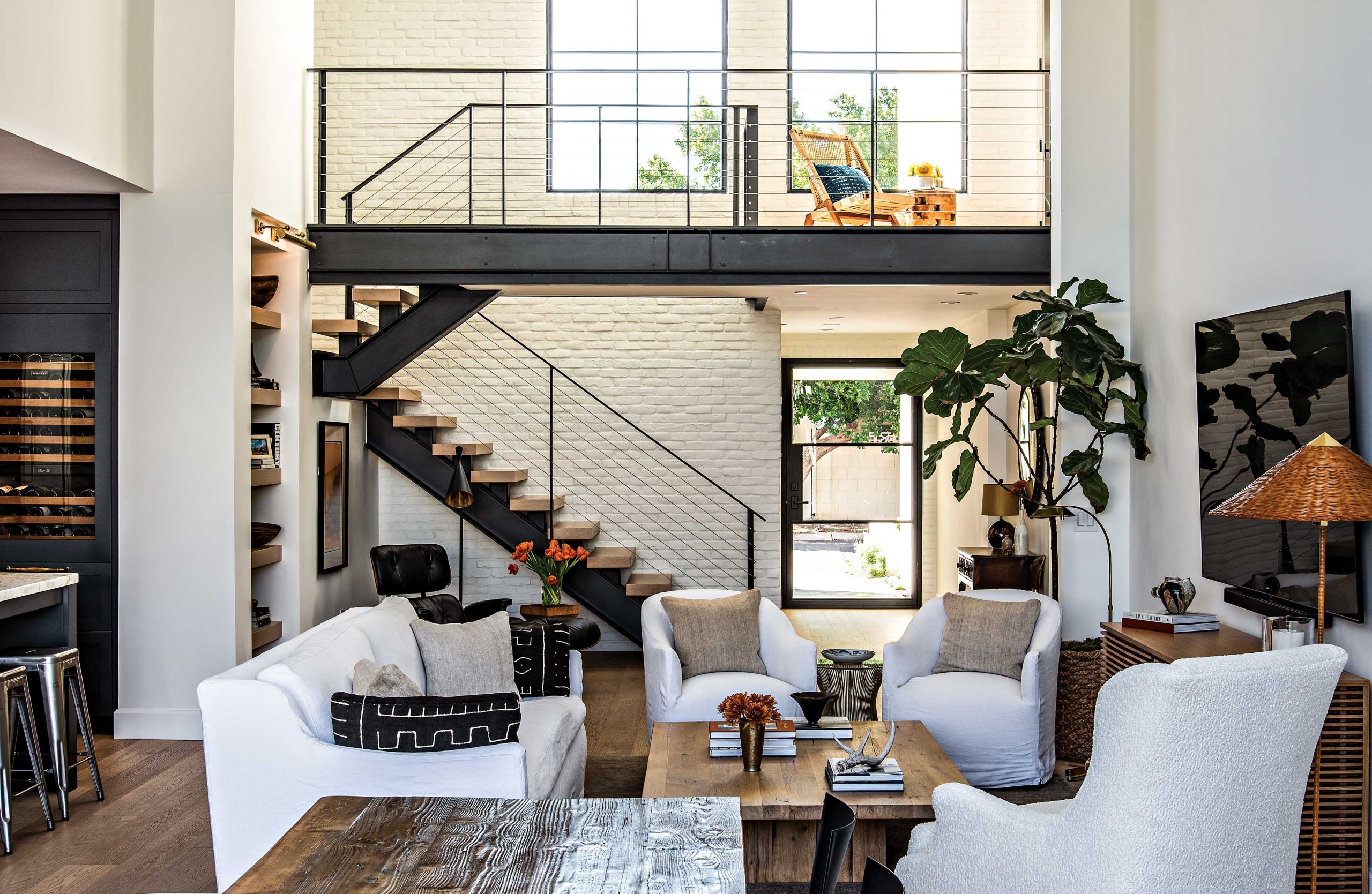 The revamped home includes a new glass entry door and larger windows to flood the interior with light. The living room’s staircase, once enclosed by a wall, leads to a landing and guest bedroom. Simple white furnishings contrast with a mix of new and vintage pieces. The revamped home includes a new glass entry door and larger windows to flood the interior with light. The living room’s staircase, once enclosed by a wall, leads to a landing and guest bedroom. Simple white furnishings contrast with a mix of new and vintage pieces.