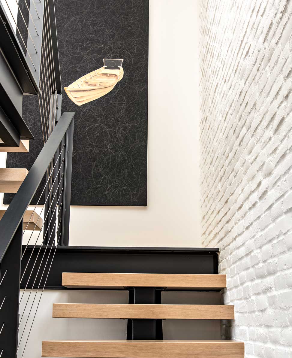 I-beams, oak slabs and stainless steel cables combine to create a sculptural staircase. Whitewashed brick gives the wall texture and interest. The painting is by the homeowners’ longtime friend, Phoenix artist Eddie Shea. I-beams, oak slabs and stainless steel cables combine to create a sculptural staircase. Whitewashed brick gives the wall texture and interest. The painting is by the homeowners’ longtime friend, Phoenix artist Eddie Shea.