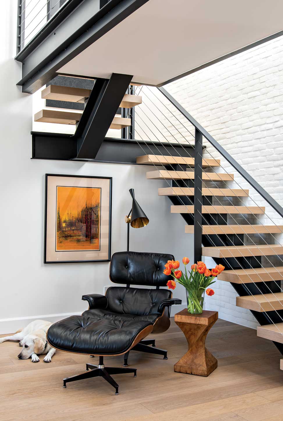 An Eames chair and ottoman create a reading spot below the staircase, a space that originally was taken up by a built-in bar. An Eames chair and ottoman create a reading spot below the staircase, a space that originally was taken up by a built-in bar.