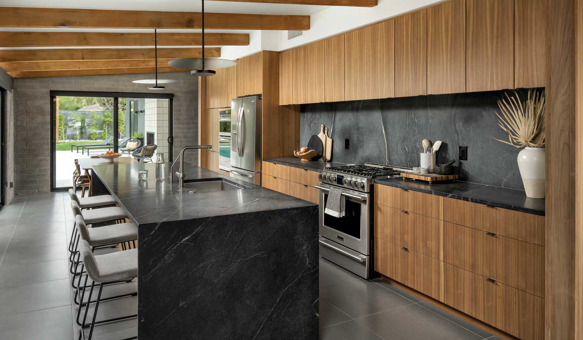 The kitchen is an open, comfortable space ideal for entertaining. “The first place everyone goes to is the island,” Contreras says, “and they all crowd around.” Black soapstone countertops play off American walnut cabinetry. The joists are made of old growth pine original to the home, though Contreras sandblasted the burnt orange paint off to “make those rhyme a little bit” with the walnut. The kitchen is an open, comfortable space ideal for entertaining. “The first place everyone goes to is the island,” Contreras says, “and they all crowd around.” Black soapstone countertops play off American walnut cabinetry. The joists are made of old growth pine original to the home, though Contreras sandblasted the burnt orange paint off to “make those rhyme a little bit” with the walnut.