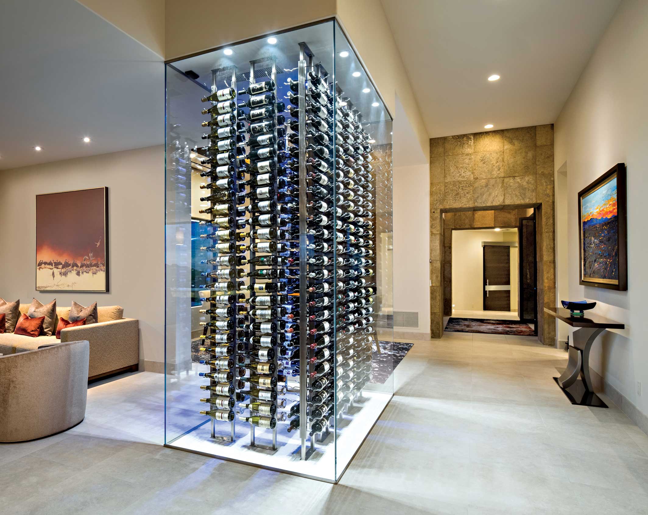 Separating an intimate dining area from the larger living spaces in a modern home, this sleek glass wine enclosure acts as an artistic focal point and features integrated lighting and metal racking that holds an impressive collection of bottles. Separating an intimate dining area from the larger living spaces in a modern home, this sleek glass wine enclosure acts as an artistic focal point and features integrated lighting and metal racking that holds an impressive collection of bottles.