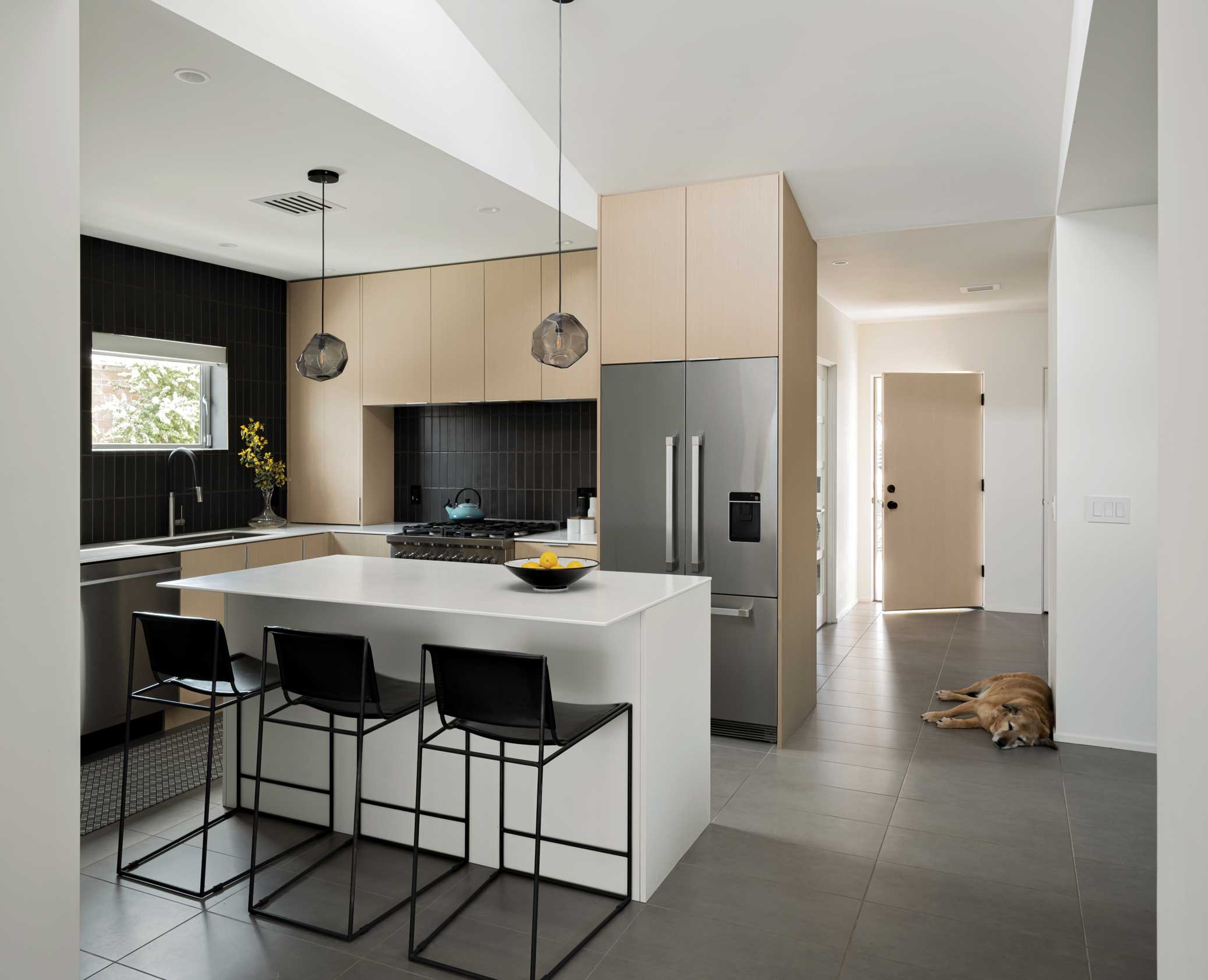 The kitchen remained in the old footprint, but opening up the walls, adding new cabinetry, appliances and a black-tiled backsplash created sleek appeal.